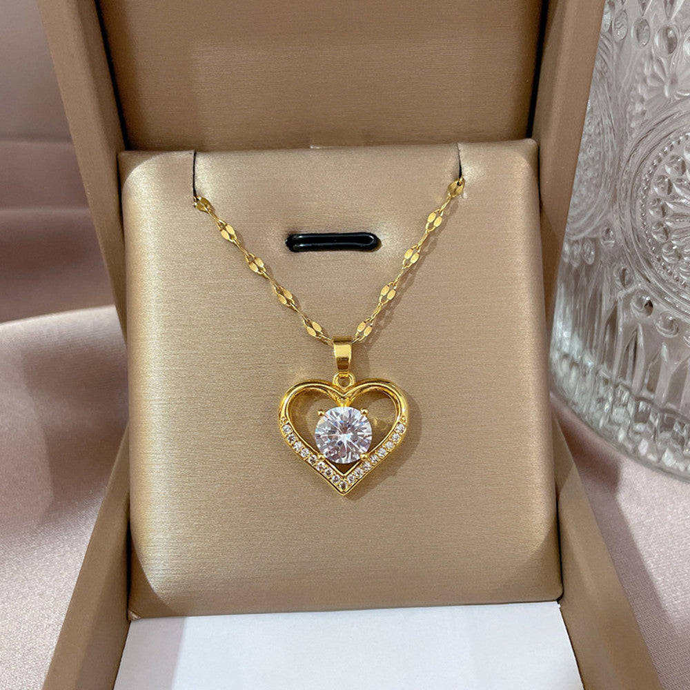 Gold heart-shaped necklace with a clear gemstone in a beige jewelry box.