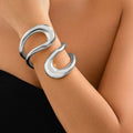 Silver bracelet on a wrist against a neutral background