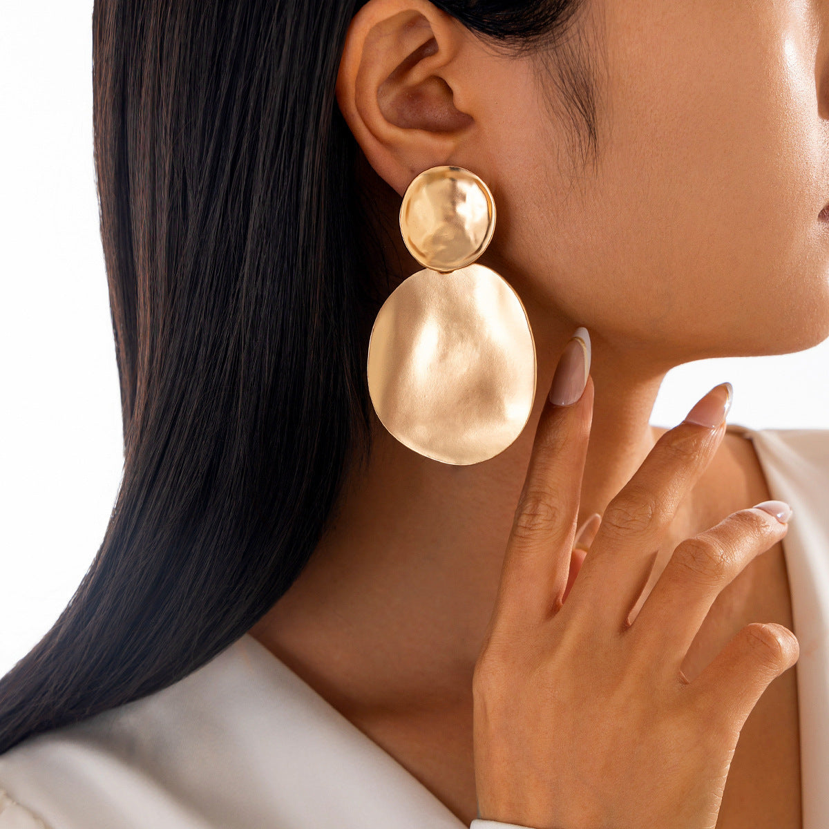 Close-up of a person wearing gold earrings with a neutral background