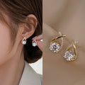 Gold earrings with clear gemstones worn by a person, close-up on ear and side view.