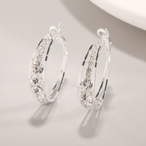 Silver hoop earrings with clear gemstones on a light gray background