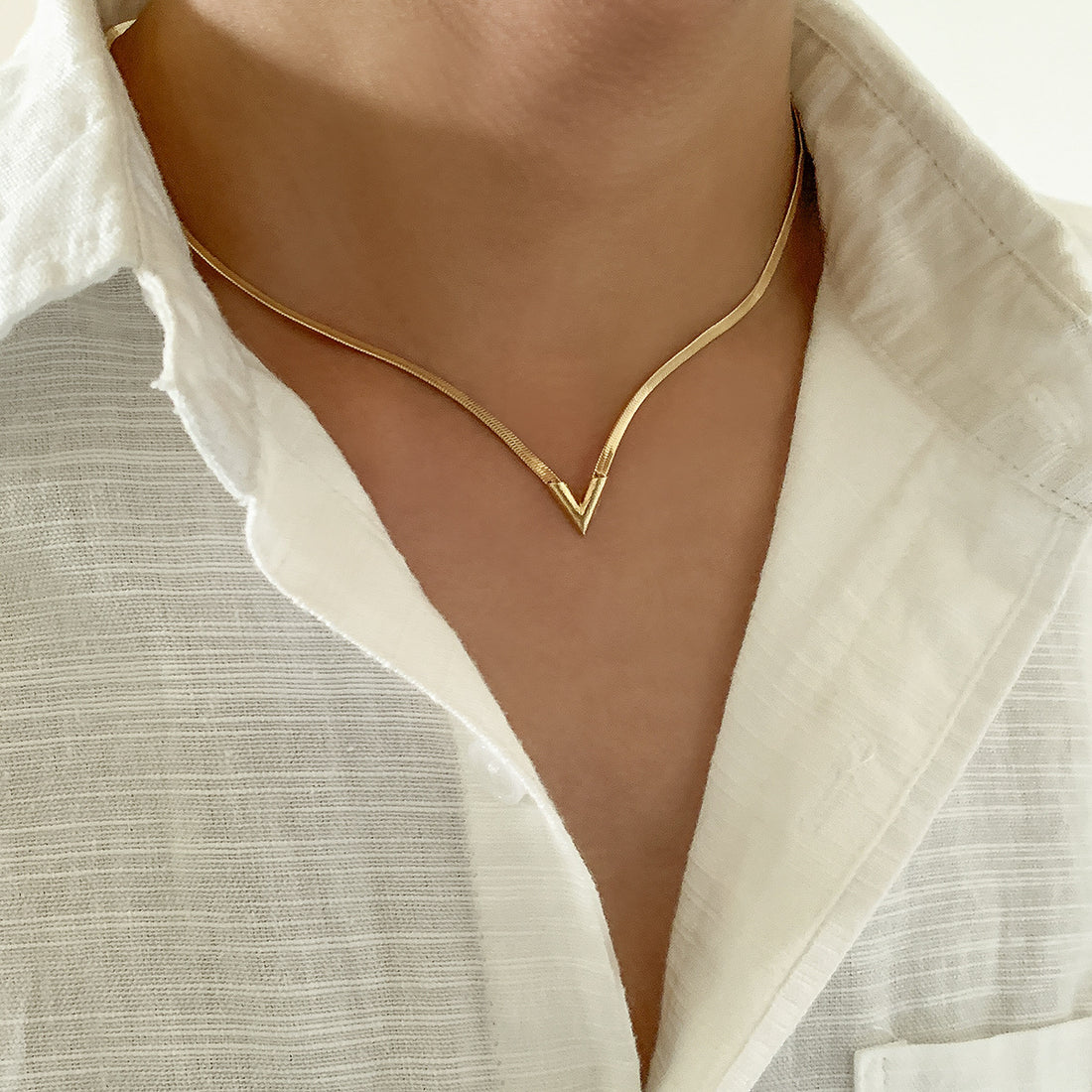 Gold necklace worn by a person with a white shirt