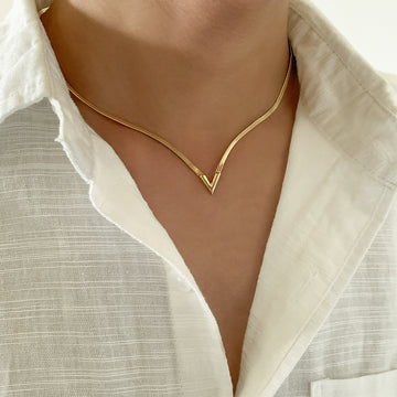 Gold necklace worn by a person with a white shirt