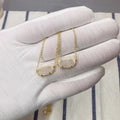 Gold necklaces on a hand wearing a white glove with a striped fabric background