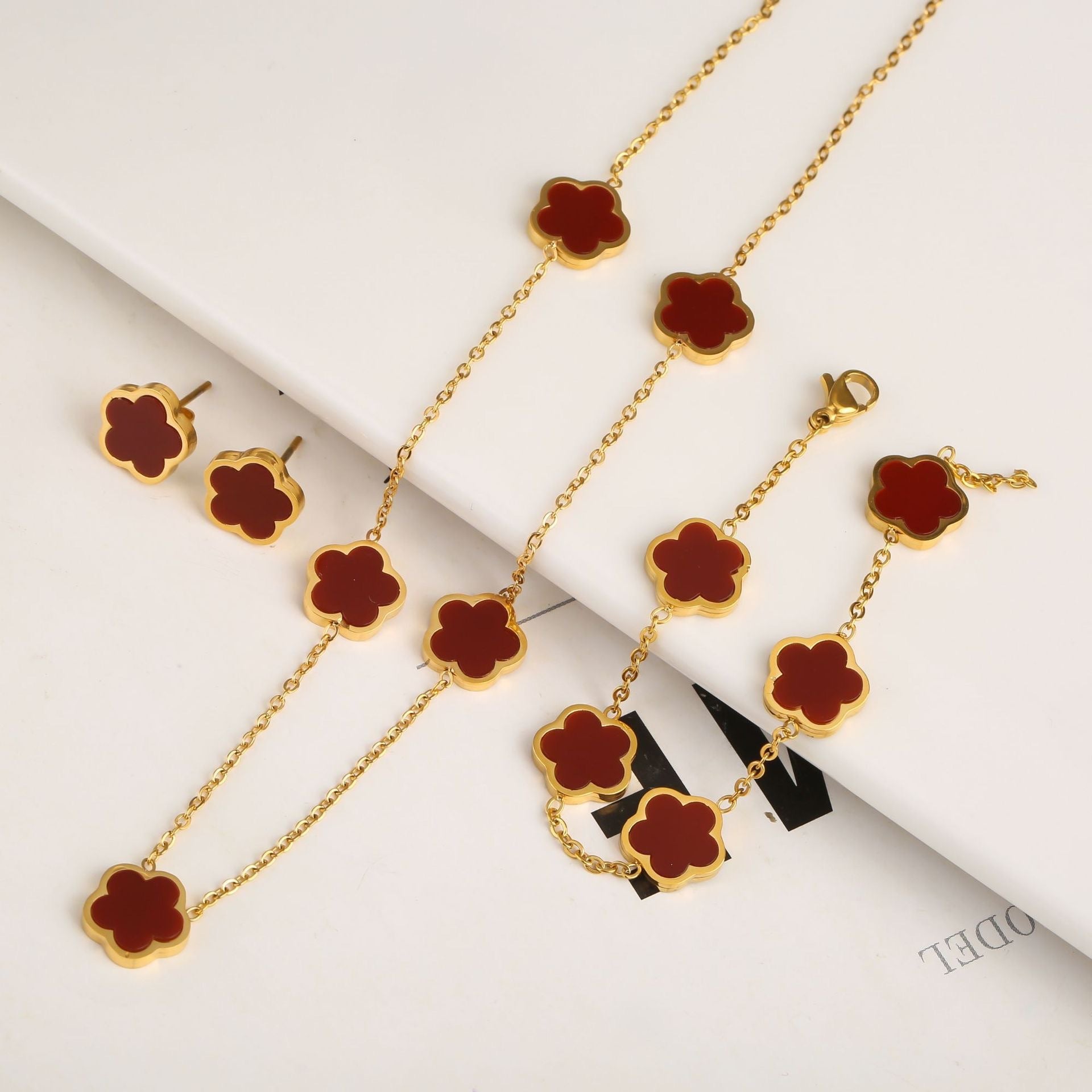 Gold necklace with red flower pendants on a white background