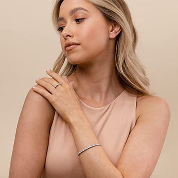 Woman wearing a ring and bracelet on a beige background