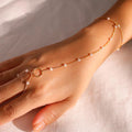 Gold anklet with pearls on a person's ankle against a neutral background