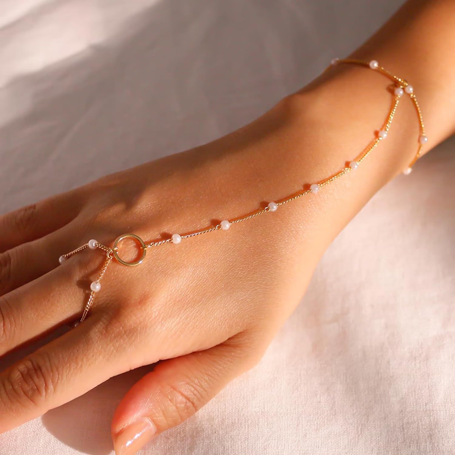 Gold anklet with pearls on a person's ankle against a neutral background