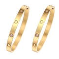 Two gold bangles with heart and diamond designs on a white background