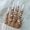 Gold rings on fingers with white nail polish on a textured gray background