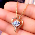Gold heart-shaped necklace with a clear gemstone held in hand