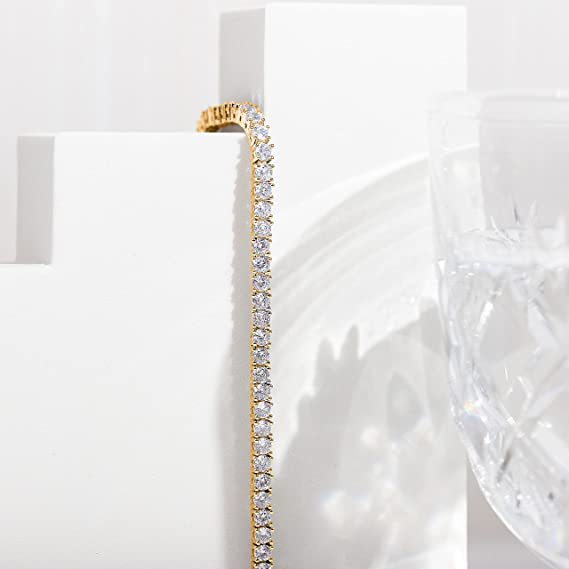 Gold bracelet with clear stones on a white surface