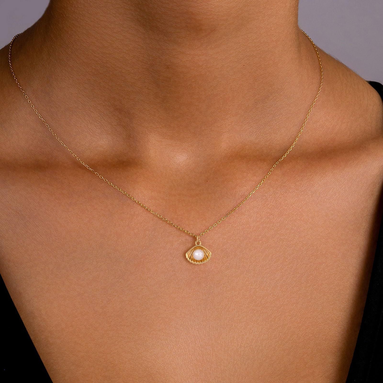 Gold necklace with a pendant on a person's neck against a neutral background