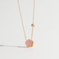 Necklace with a pink flower pendant on a light gray background