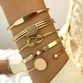 Gold bracelets on a wrist with a neutral background