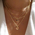 Gold necklaces with circular pendants on a person wearing a white top.