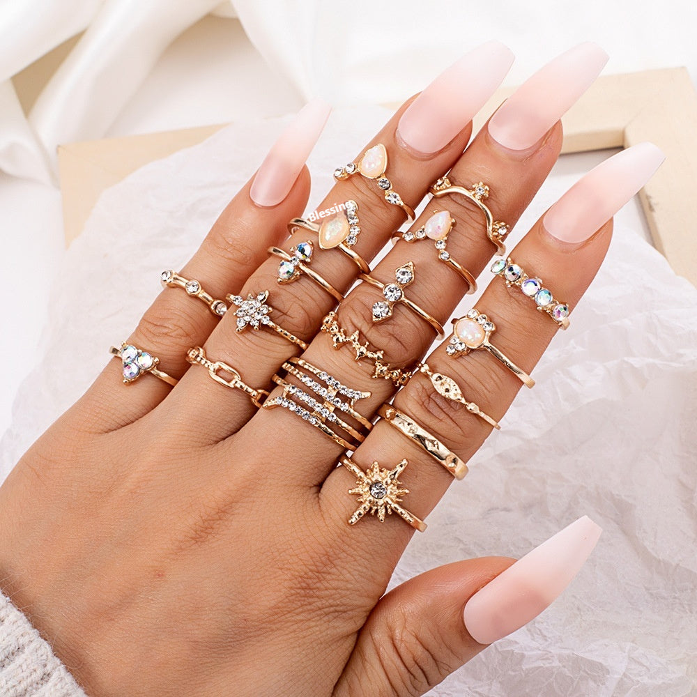 Hand wearing multiple gold rings with gemstones on a neutral background