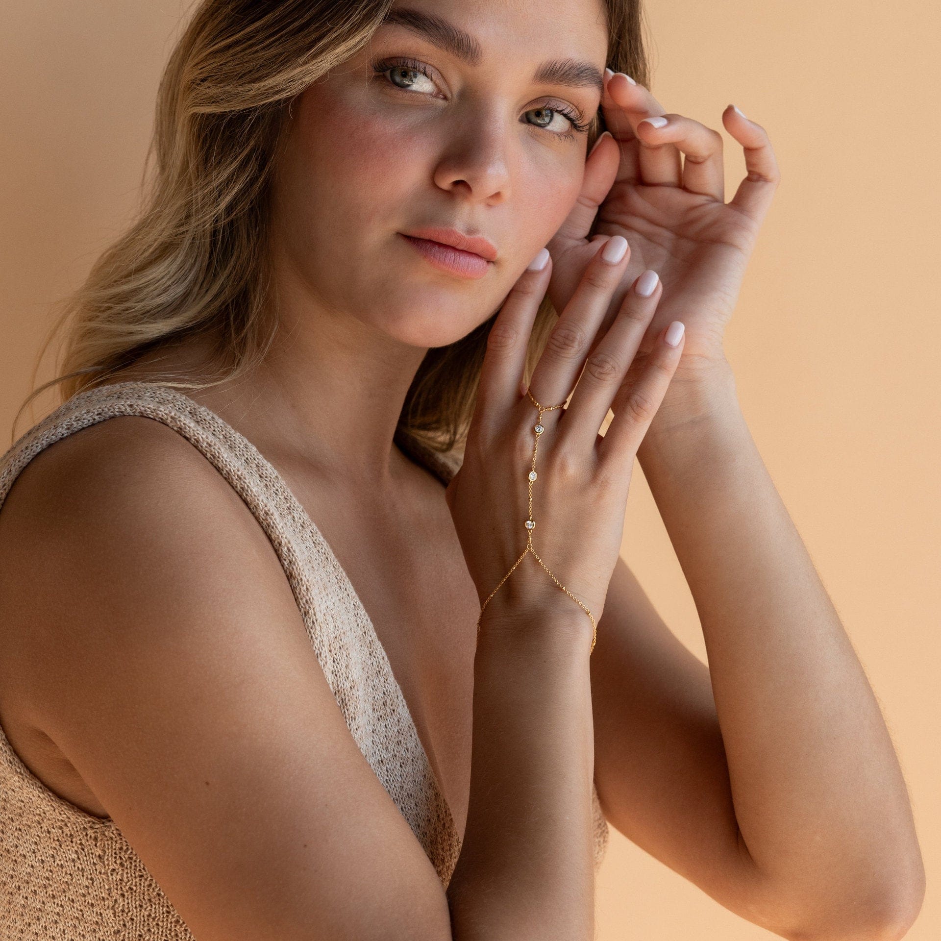 Woman with hands near face against a beige background