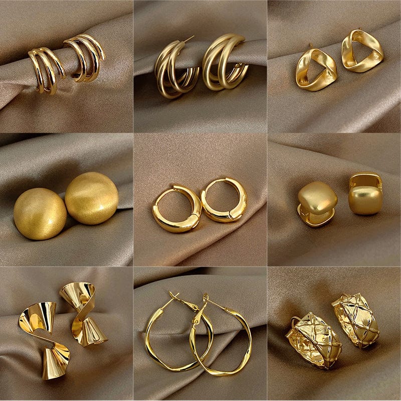 Collection of gold earrings on a beige fabric background