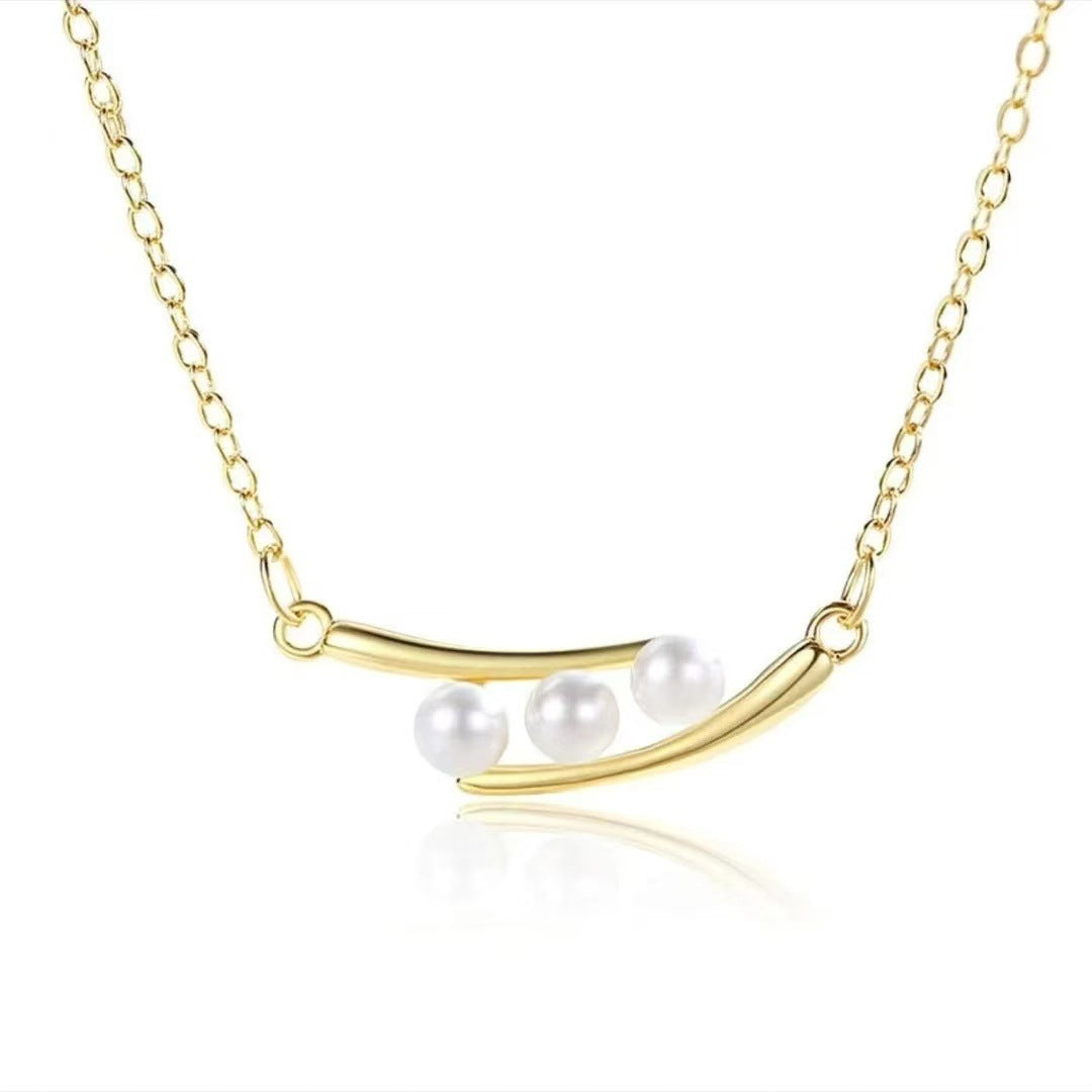 Gold necklace with three pearls on a white background