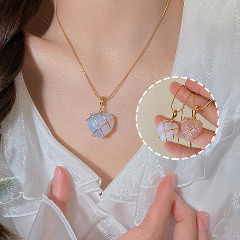 Necklace with a pendant and matching earrings held by a hand, on a white background.