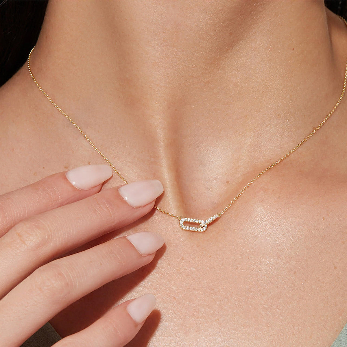 Gold necklace with a diamond pendant on a person's neck