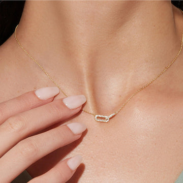Gold necklace with a diamond pendant on a person's neck