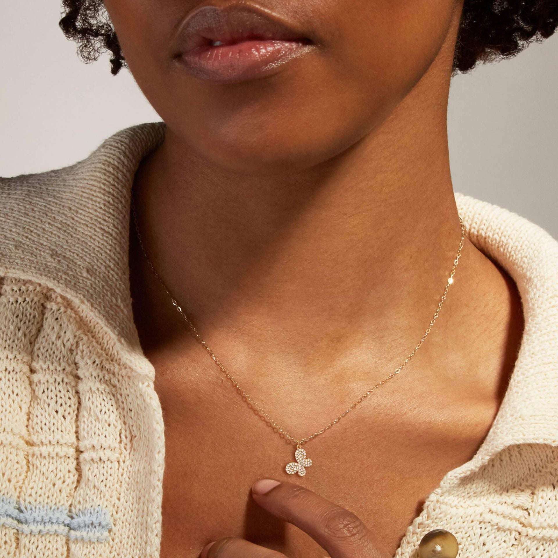 Close-up of a person wearing a delicate butterfly necklace.
