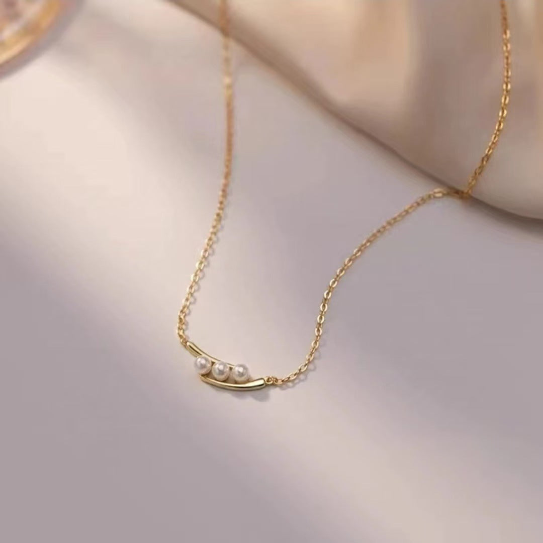 Gold necklace with pearls on a soft beige background