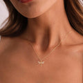 Gold necklace with a dragonfly pendant on a person's neck